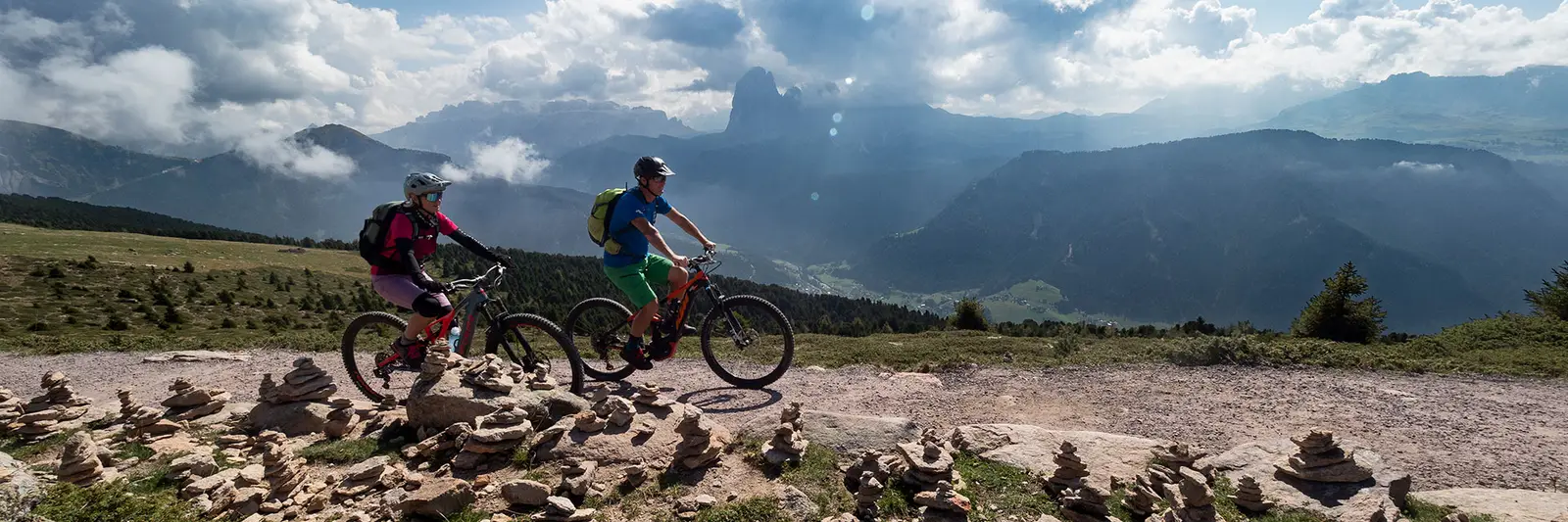 Zwei E-MTB-Fahrer auf einem felsigen Plateau mit Steinmännchen und Bergpanorama