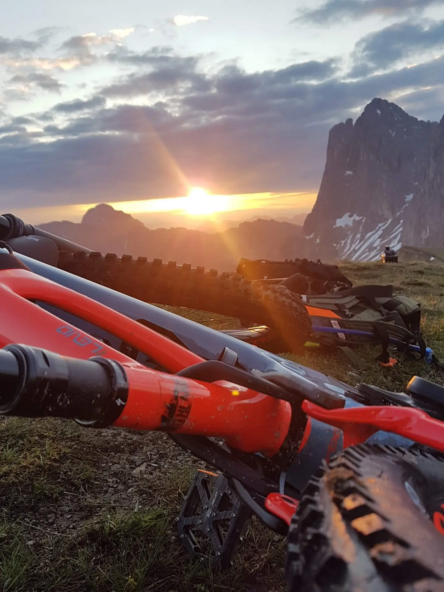Alba sulle cime dolomitiche, in primo piano manubrio e forcella rossi di una e-MTB