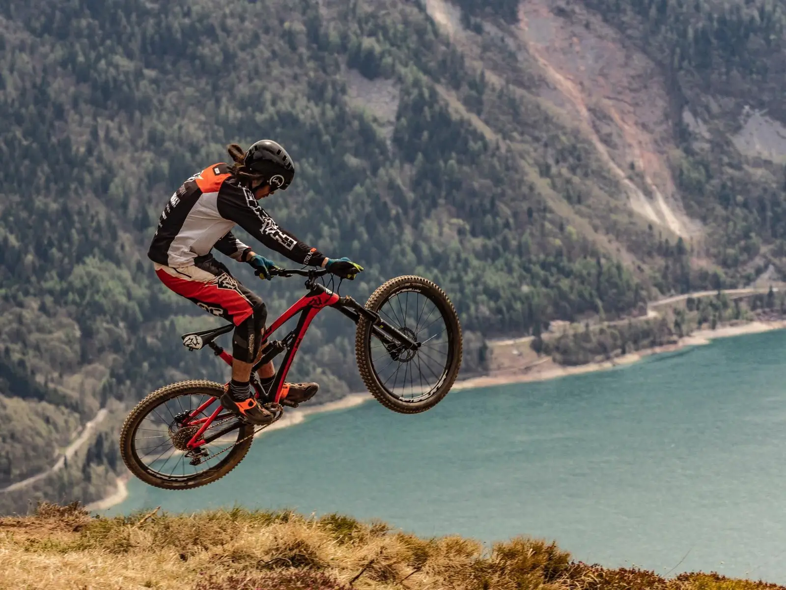 Mountain biker jumping above a mountain lake