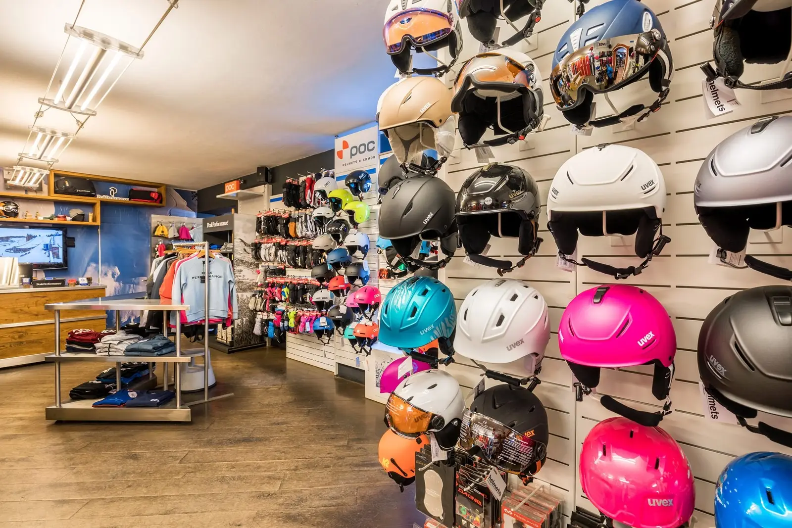 Shop interior: wall of ski helmets (Uvex, POC) and apparel