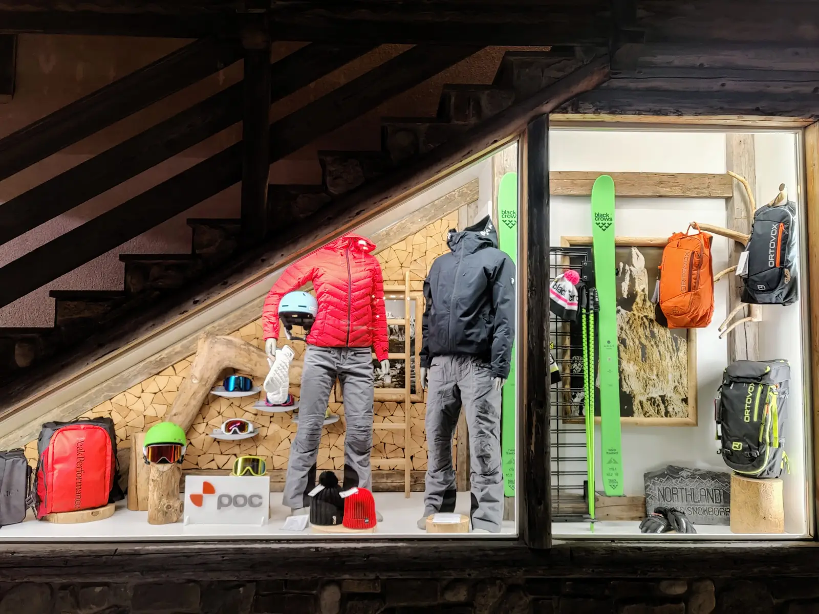 Schaufenster am Abend mit Jacken, Ski und Rucksäcken