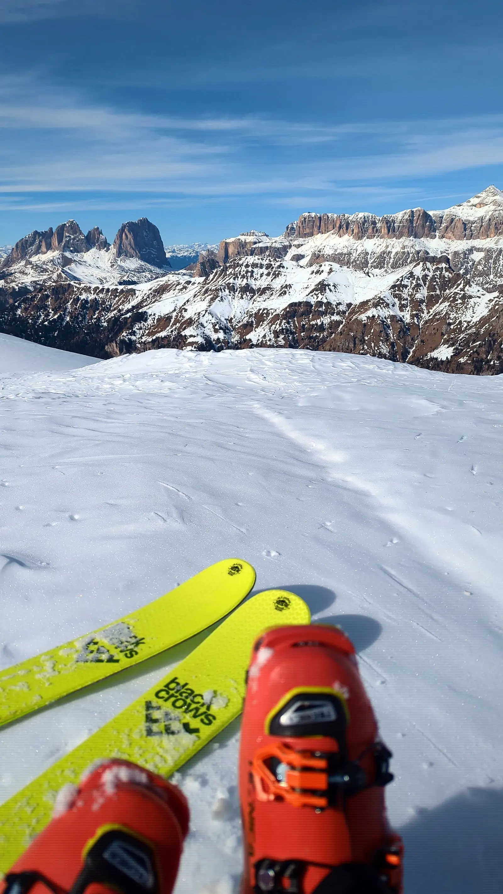 Skischuhe und gelbe Ski mit Blick auf die Sella