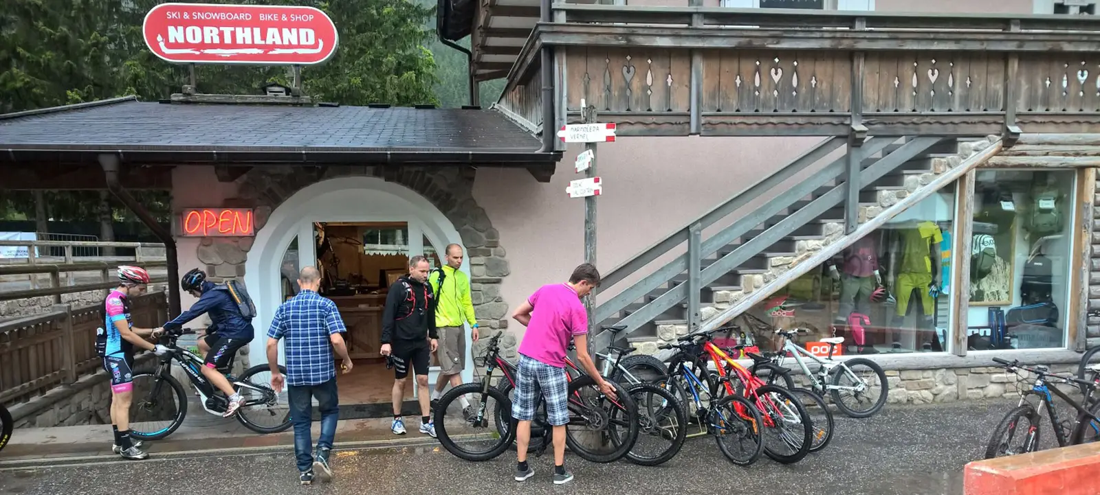 Ingresso del negozio in estate con clienti ed e-bike, insegna rossa “Northland”